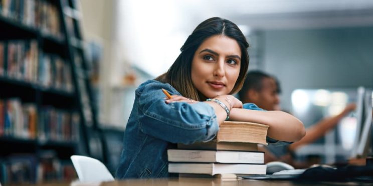 A student with a stack of books in a library