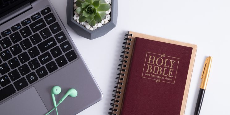 Bible, laptop, and headphones on worktable