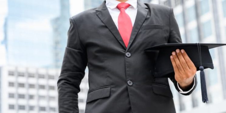 Business professional holding graduation cap.