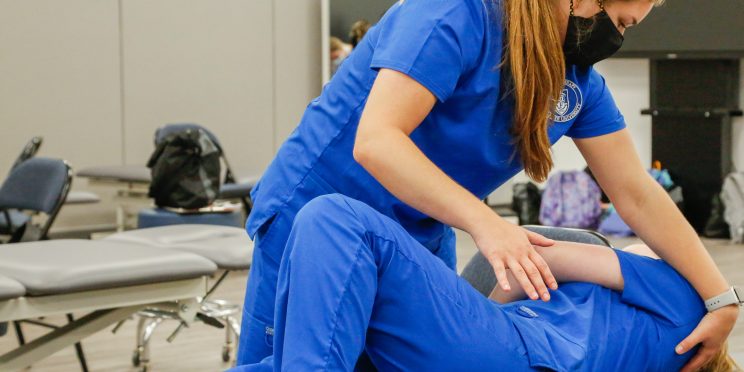 Physical Therapy students practice during a lab session. They have earned accreditation.
