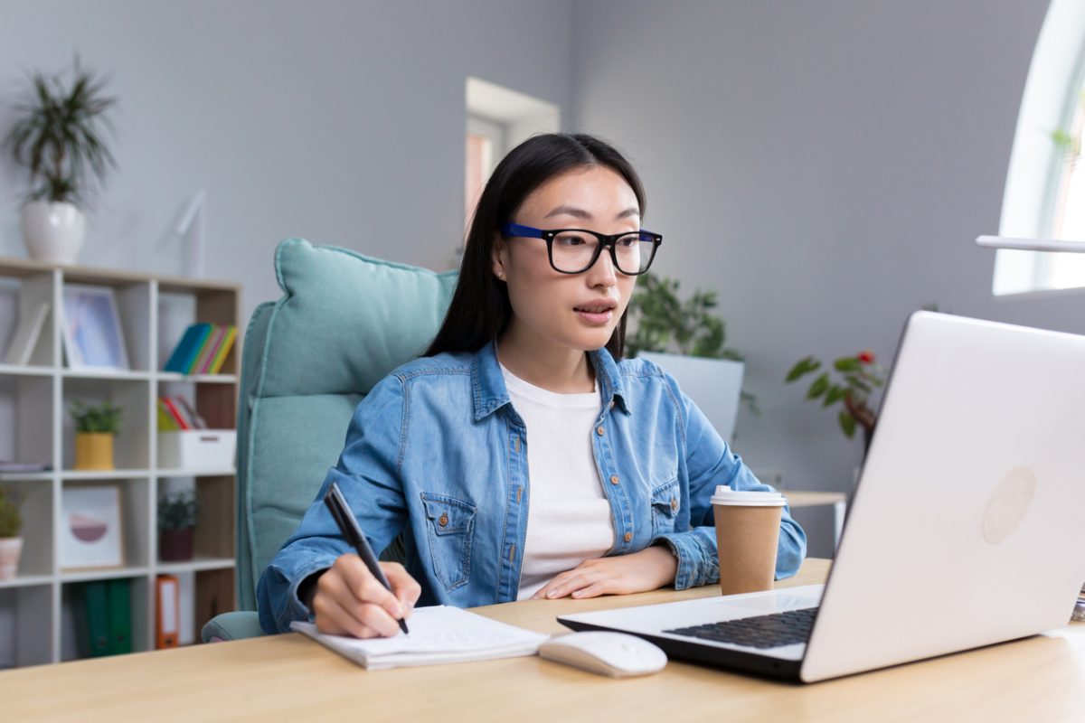 College student working on laptop at desk with coffee and notepad