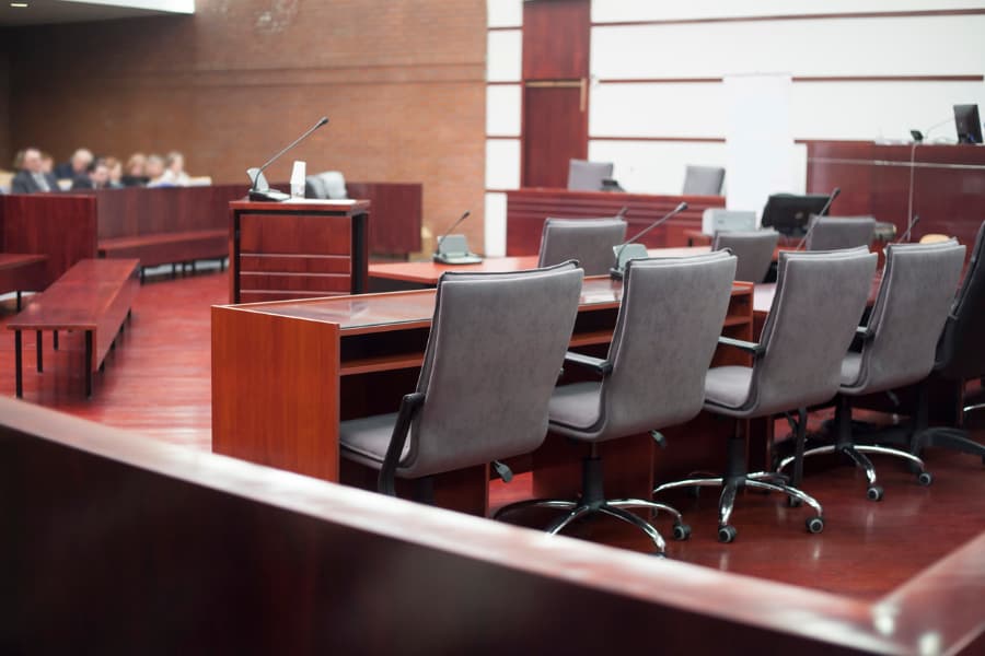 Courtroom with podium, row of gray chairs on wheels, and jurors in background