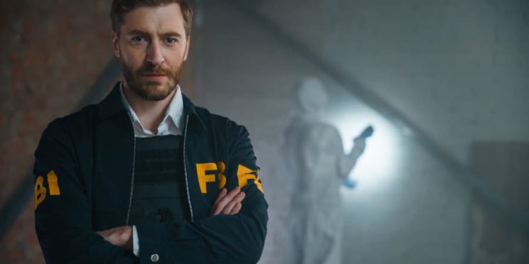 FBI agent standing with arms crossed at crime scene