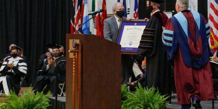 Dale Kirkland, left and President Mike Williams, right confer an honorary Doctorate of Humane Letters to David Shannon, center.