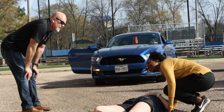 Student assesses the responsiveness of her "unconscious" peer during a First-Aid CPR class demonstration.