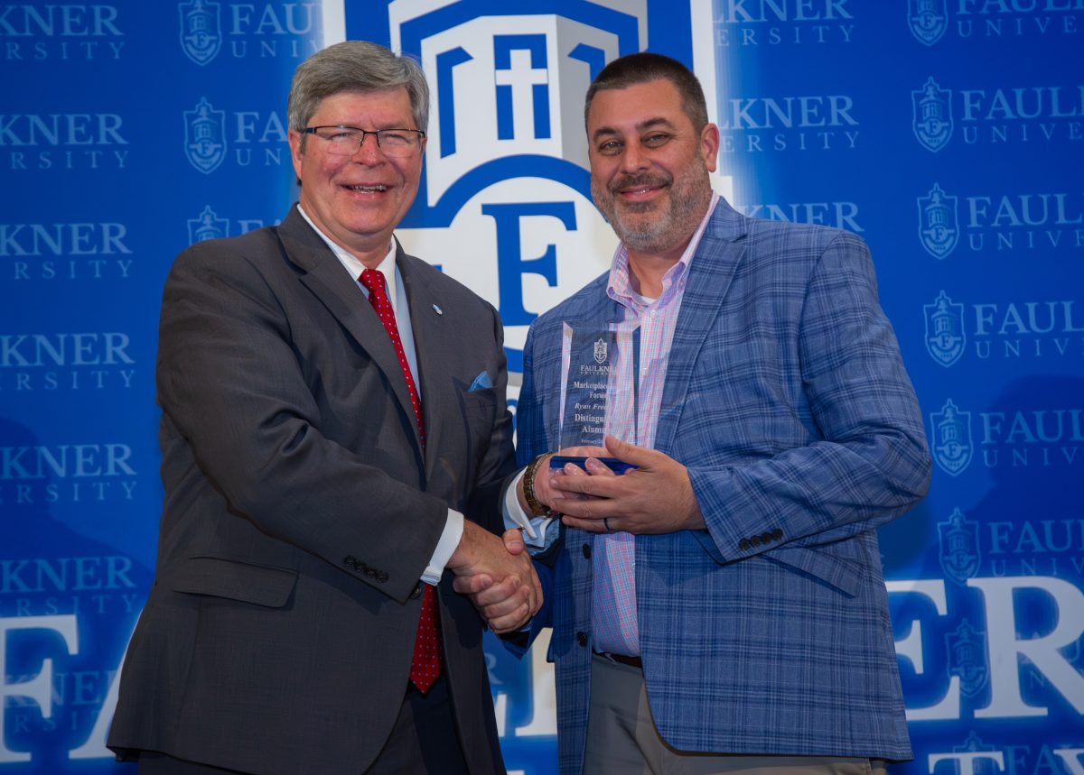 Ryan Frederick receives the Distinguished Alumnus Award from Faulkner President Mitch Henry.