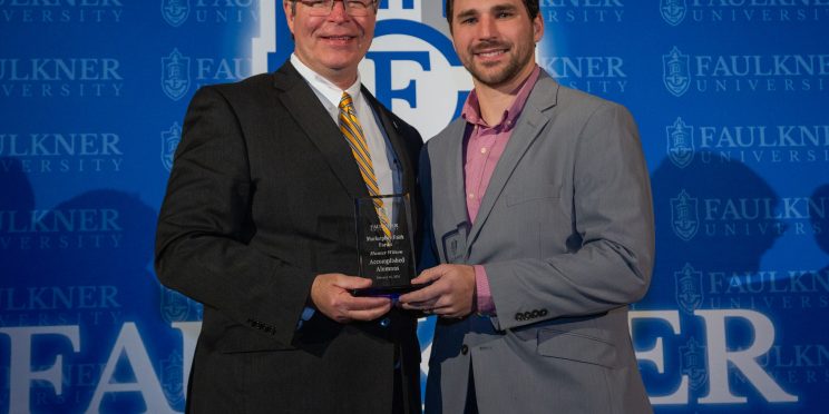 President Mitch Henry presents Hunter Wilson with the Accomplished Alumnus Award in front of a Faulkner blue backdrop.