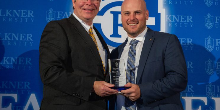 President Mitch Henry, left, presents John Dockins with the Distinguished Alumnus of the Year Award.