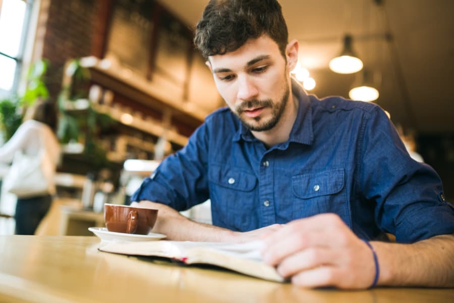 Student studying Bible while drinking coffee