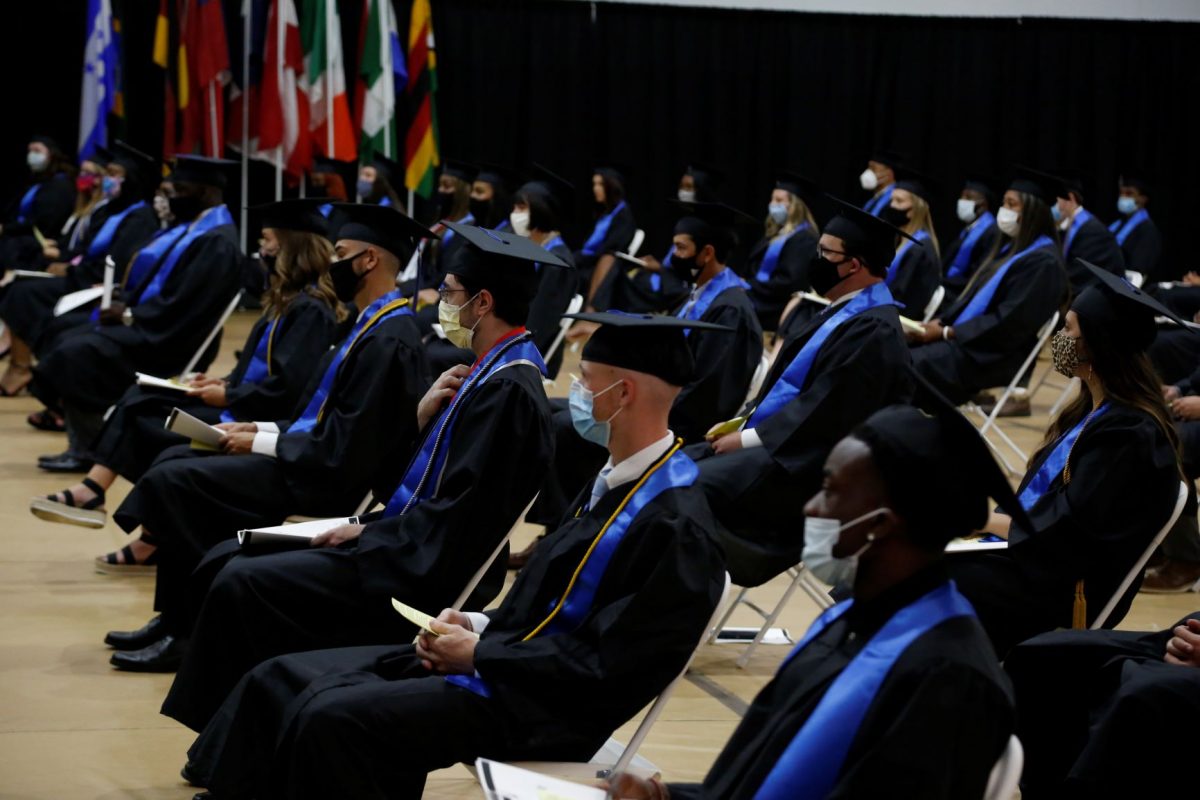 Graduates are spaced 6-feet apart as they await to walk the stage during the 2020 Spring commencement ceremony on August 8.