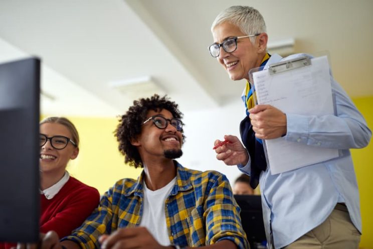 Professor helps students at computer