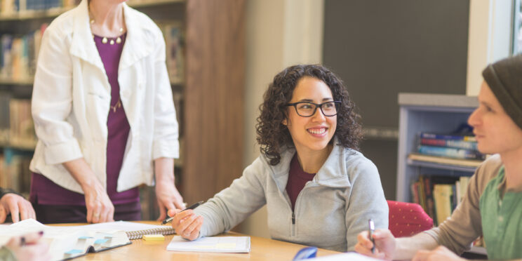 Professor with group of students at table in library
