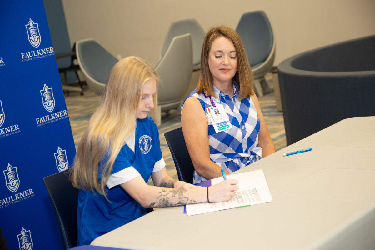 Gabby Pfaff signs an apprentice agreement with Baptist Health with Carman Dean, education director at Baptist East and apprenticeship coordinator sitting next to her.