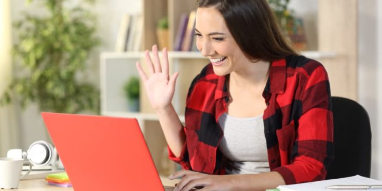 Smiling college student greets classmates on a video call