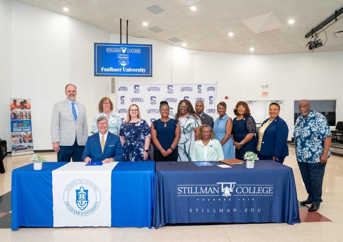 Seated at the table, l-r President Mitch Henry and Yolanda W. Page, President of Stillman College. Staff and faculty from both colleges stand behind them.