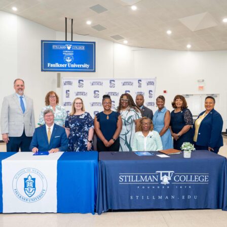 Seated at the table, l-r President Mitch Henry and Yolanda W. Page, President of Stillman College. Staff and faculty from both colleges stand behind them.
