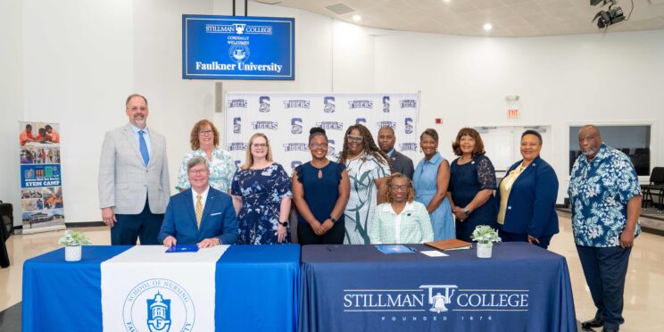 Seated at the table, l-r President Mitch Henry and Yolanda W. Page, President of Stillman College. Staff and faculty from both colleges stand behind them.