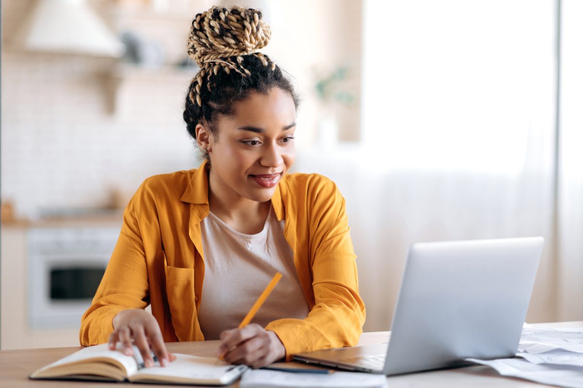 University student with laptop and book interacts with online learning platform