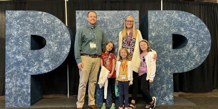 Matt Wallin, left, stands with his wife and children in front of the letters PTP.