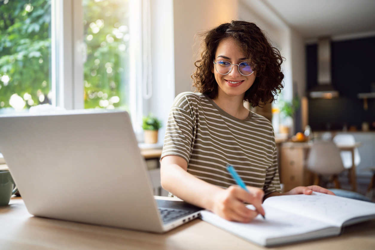 Student sitting in front of laptop and taking notes