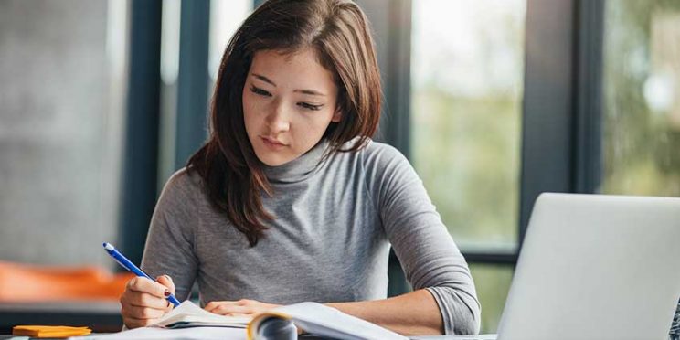 College Student Studying with Notebook and Laptop