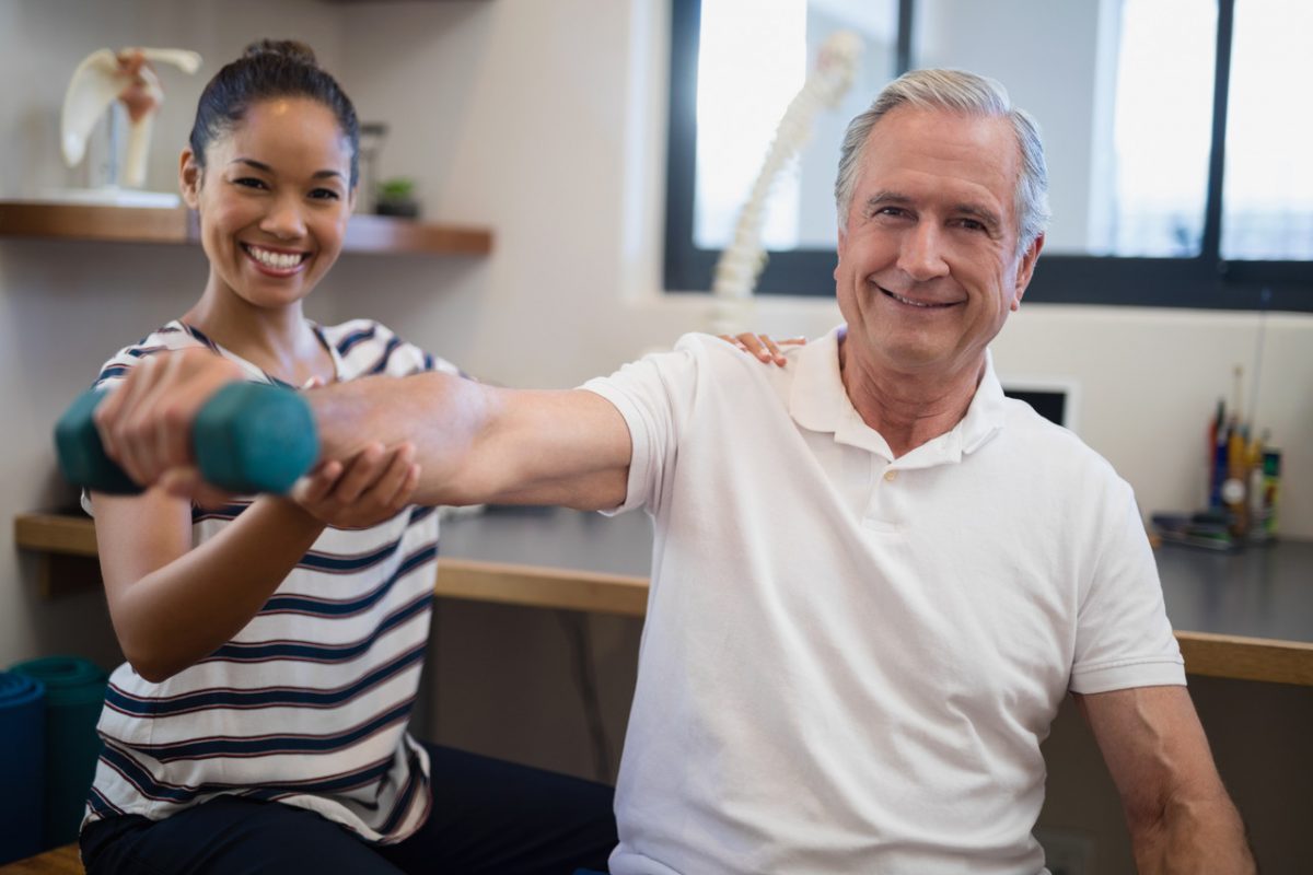 Therapist helps elderly patient with physical therapy exercises using a dumbbell. Physical Therapy is the most recent addition to Faulkner's programs after receiving accreditation status.