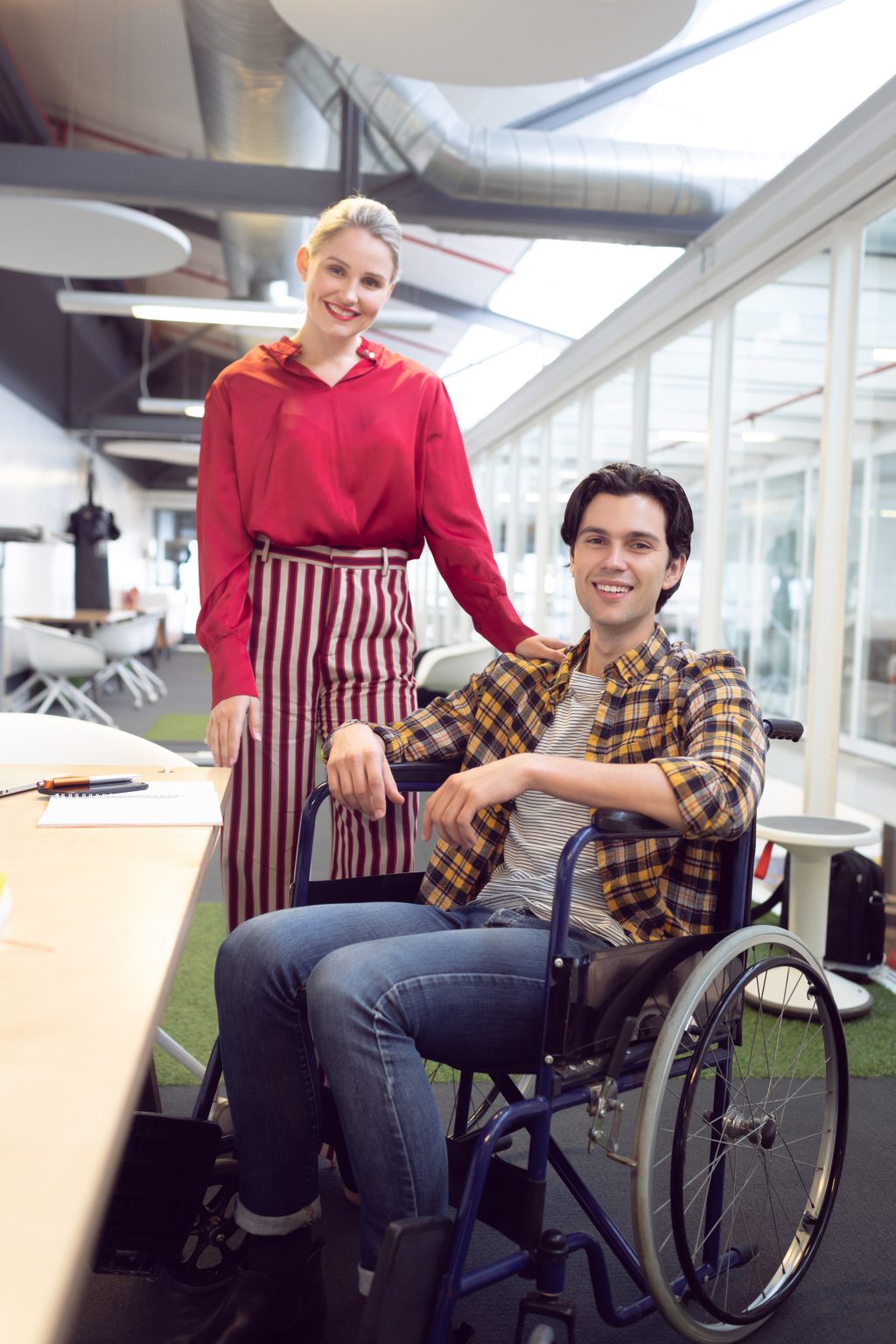 Front view of Caucasian male and female fashion designers looking at camera at desk in office