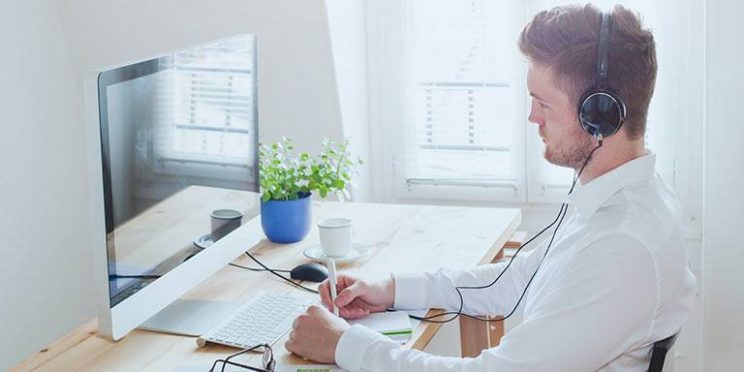 Man with Headphones Taking Online Class on Apple Computer