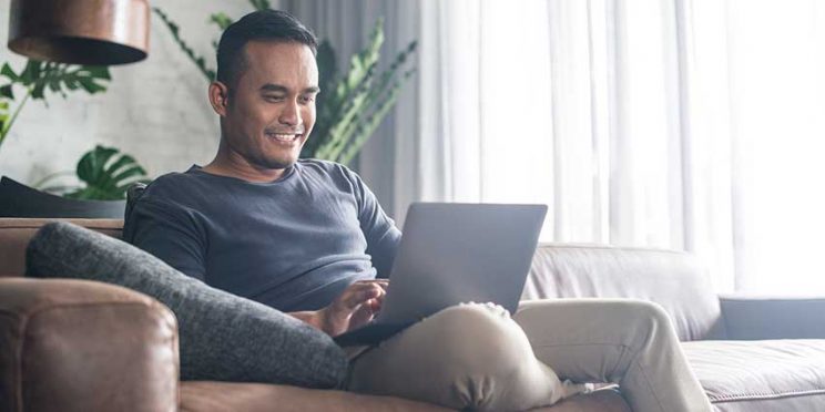 Man on Couch Typing on Laptop