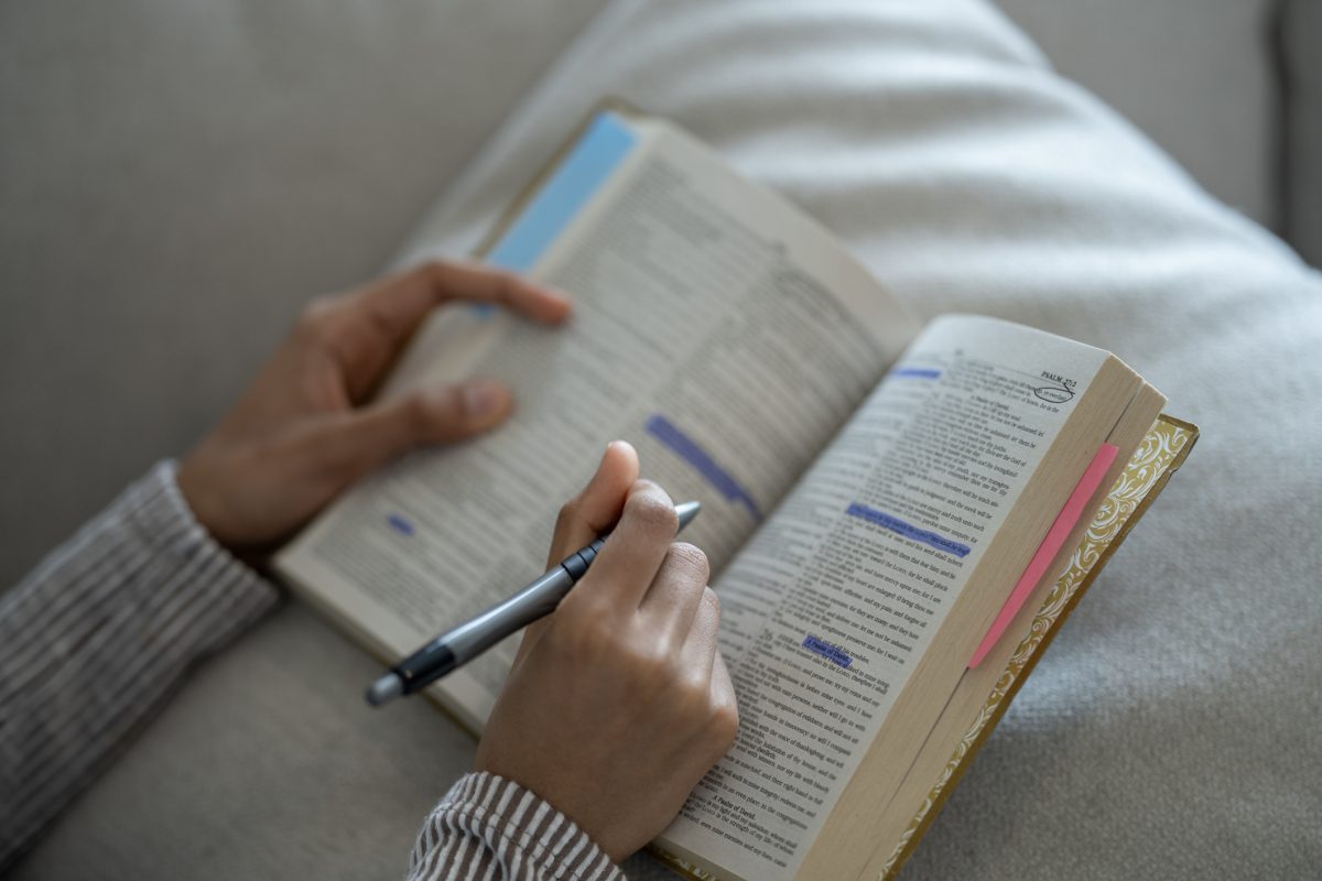 Person reading Bible passages and taking notes