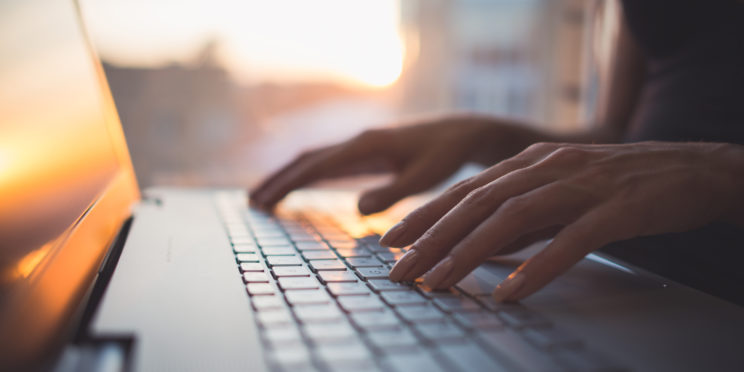 Hands typing on a computer.