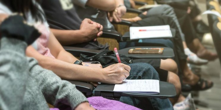 Students Sitting in Row Taking Notes in Class
