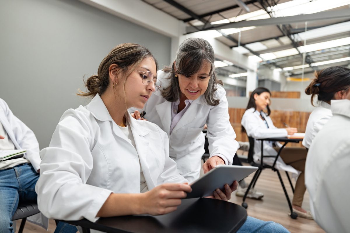 Teacher helping nursing student on tablet