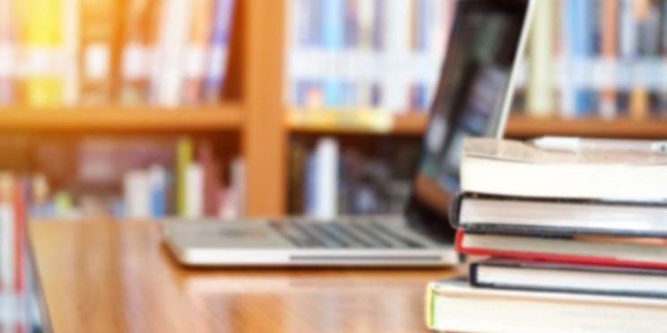 Stack of Textbooks Next to Laptop